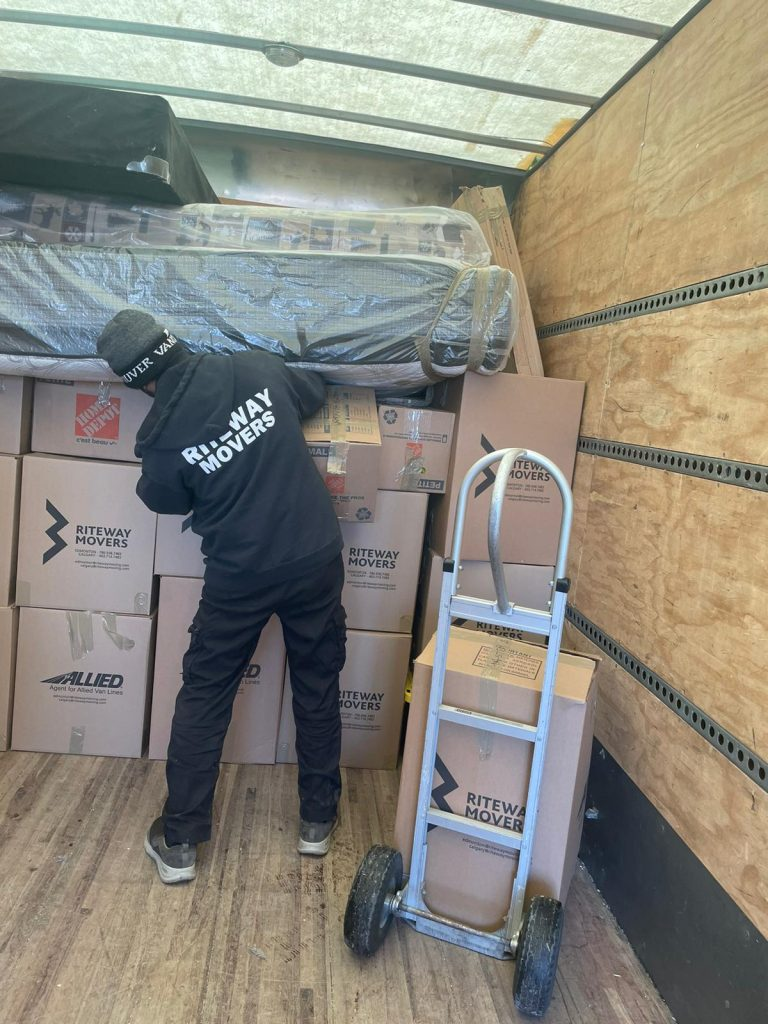 Riteway mover preparing a wrapped mattress for transport inside a truck