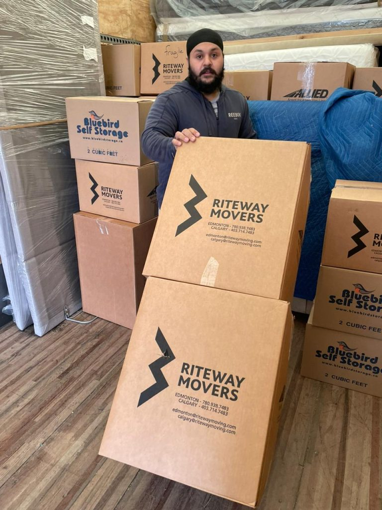 Riteway Movers team member holding a branded moving box in a storage facility