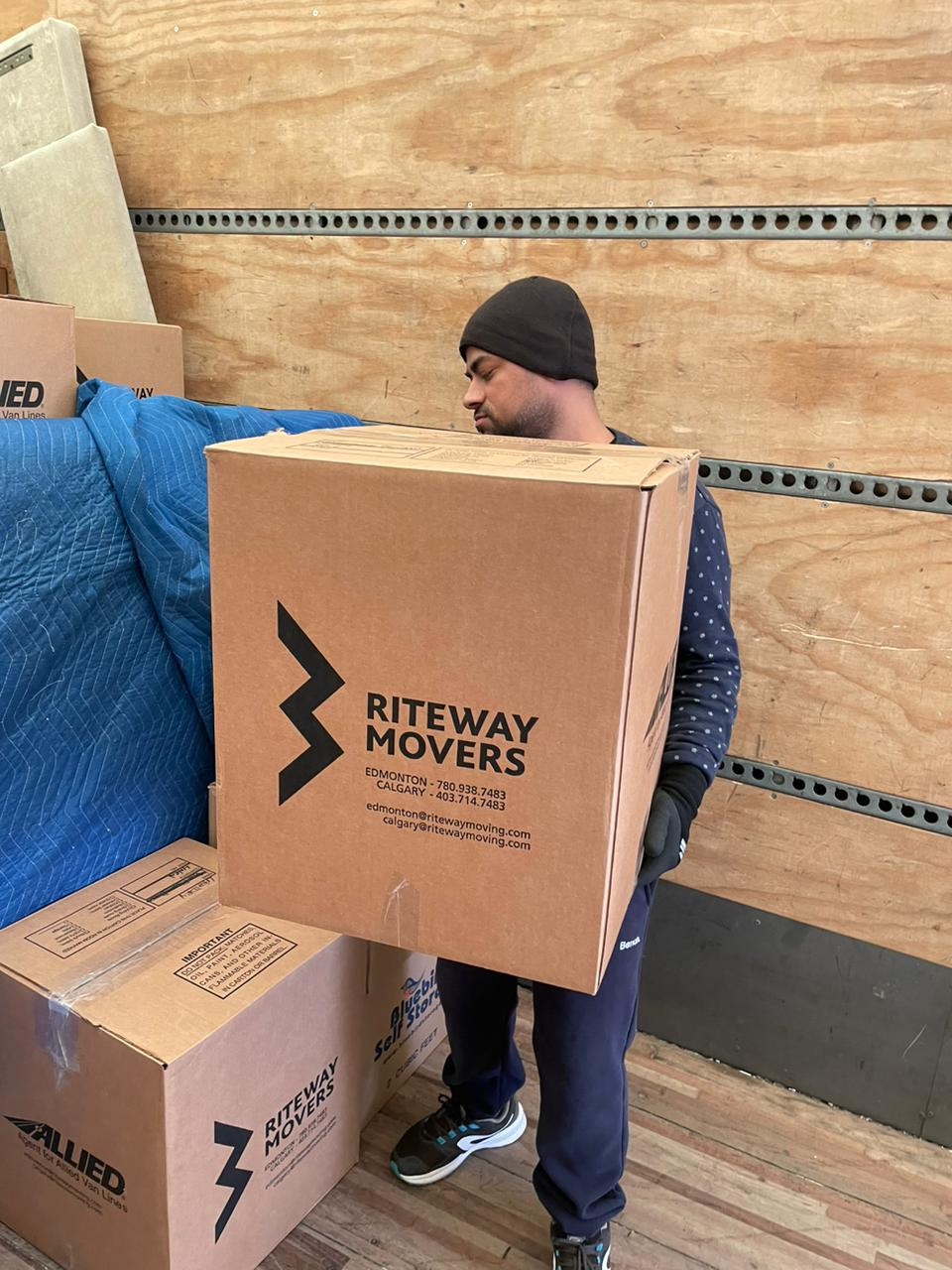 Riteway mover carefully carrying a box inside a moving truck.