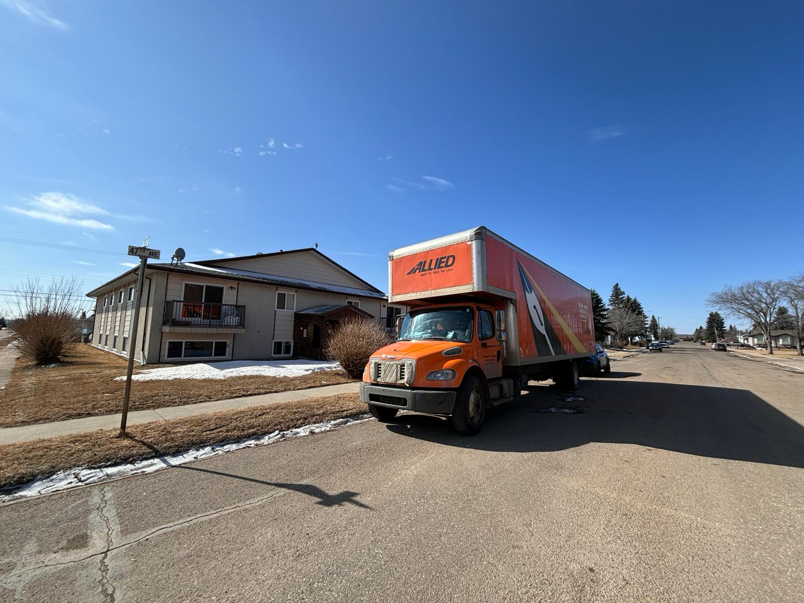 Moving truck parked on a residential street beside a home